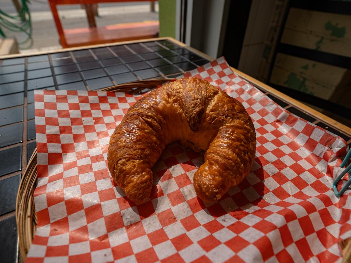 An all-butter croissant on red checked paper