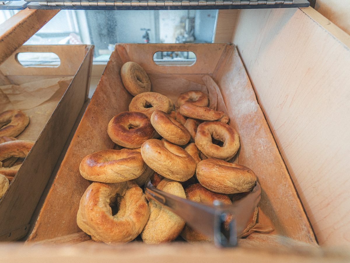 Wood-fired plain bagels piled in a wooden crate